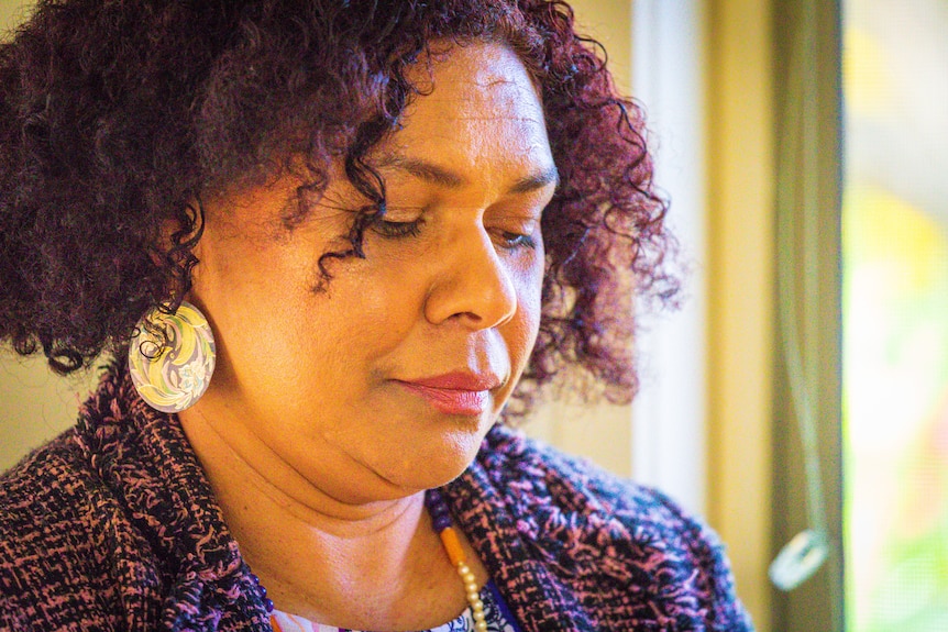 A woman with curly hair looking down.