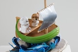 Wooden boat sculpture with plastic cat and owl inside
