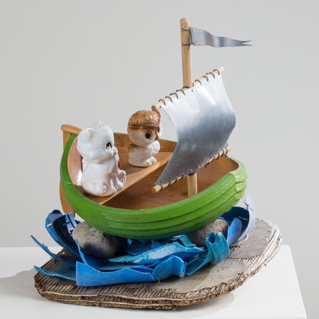 Wooden boat sculpture with plastic cat and owl inside