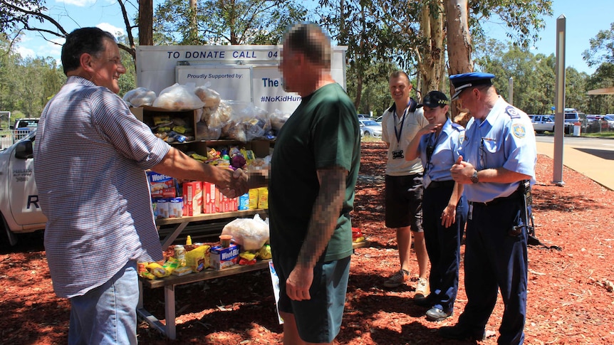 Blurred image of prisoner shaking hands with charity owner when handing over food donation.