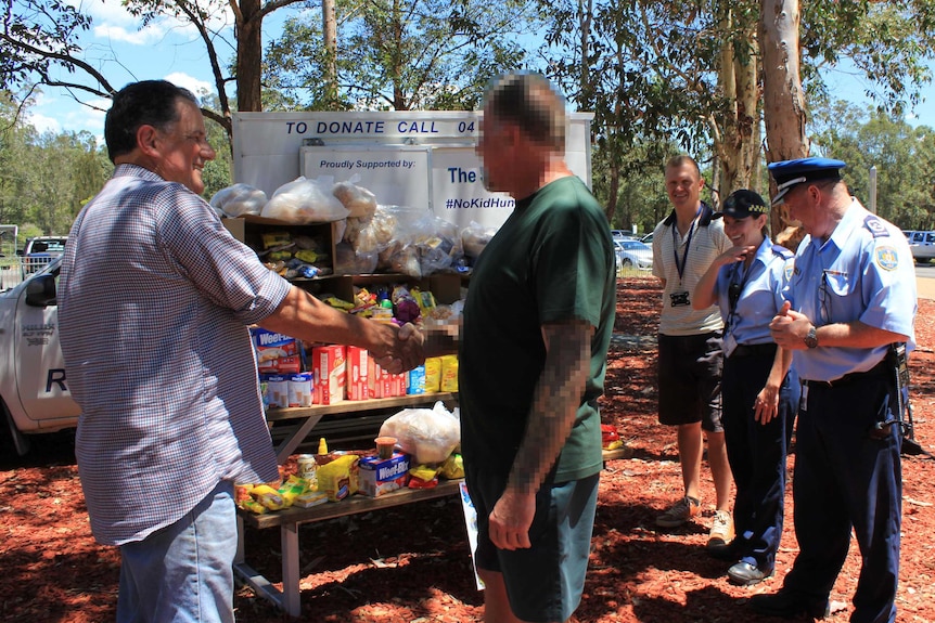 Blurred image of prisoner shaking hands with charity owner when handing over food donation.