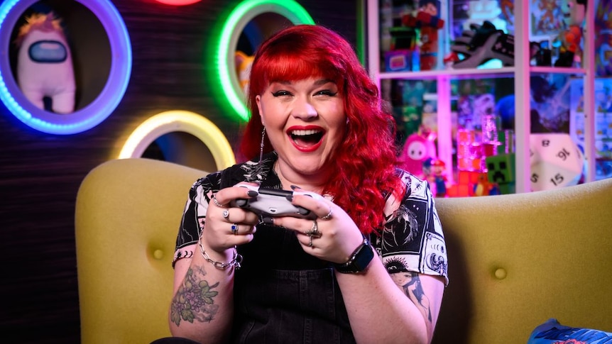 Red-haired woman laughing, holding game controller; neon-lit room with colorful toys and decor.