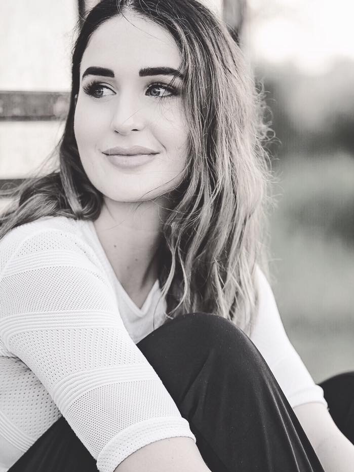 A black and white image of a striking young woman with heavy eyebrows and dark hair looking to the left out of the image.