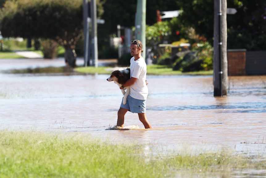 A man carries a dog through flood water