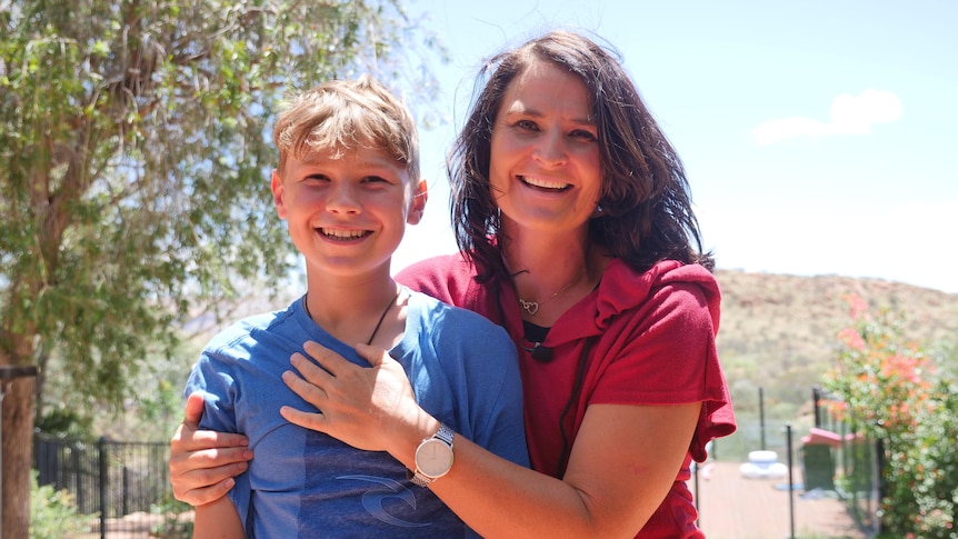 young boy in blue shirt and woman with brown hair and red shirt in front of ranges