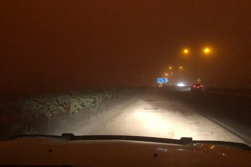 A car stopped on the side of the road in what looks like night time.