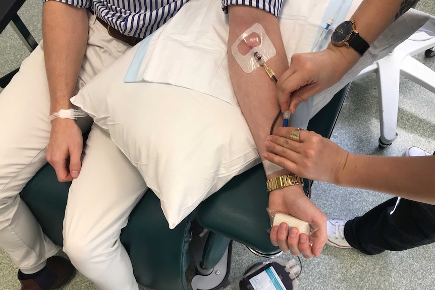 A view from above as blood is drawn from Ben Henry's arm by a nurse.