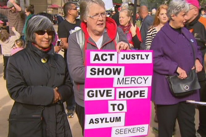 Women with sign at Melbourne refugee rally