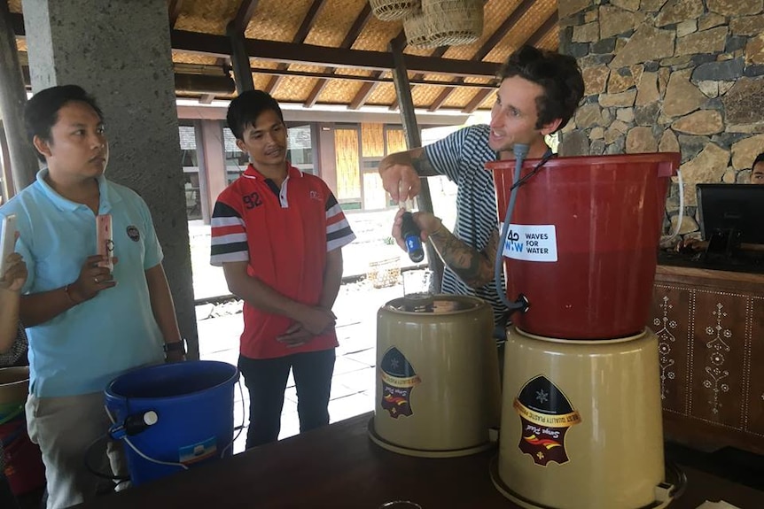 Kain Sissons shows two Indonesian men how to use a water filter