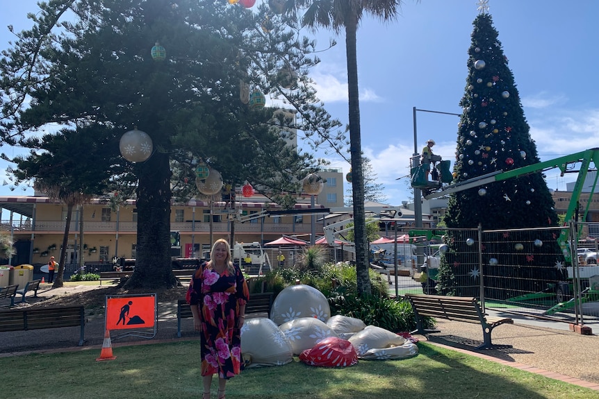 Woman in pink floral dress stands in front 