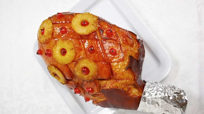 A glazed ham sitting on a tray on a white table