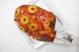 A glazed ham sitting on a tray on a white table