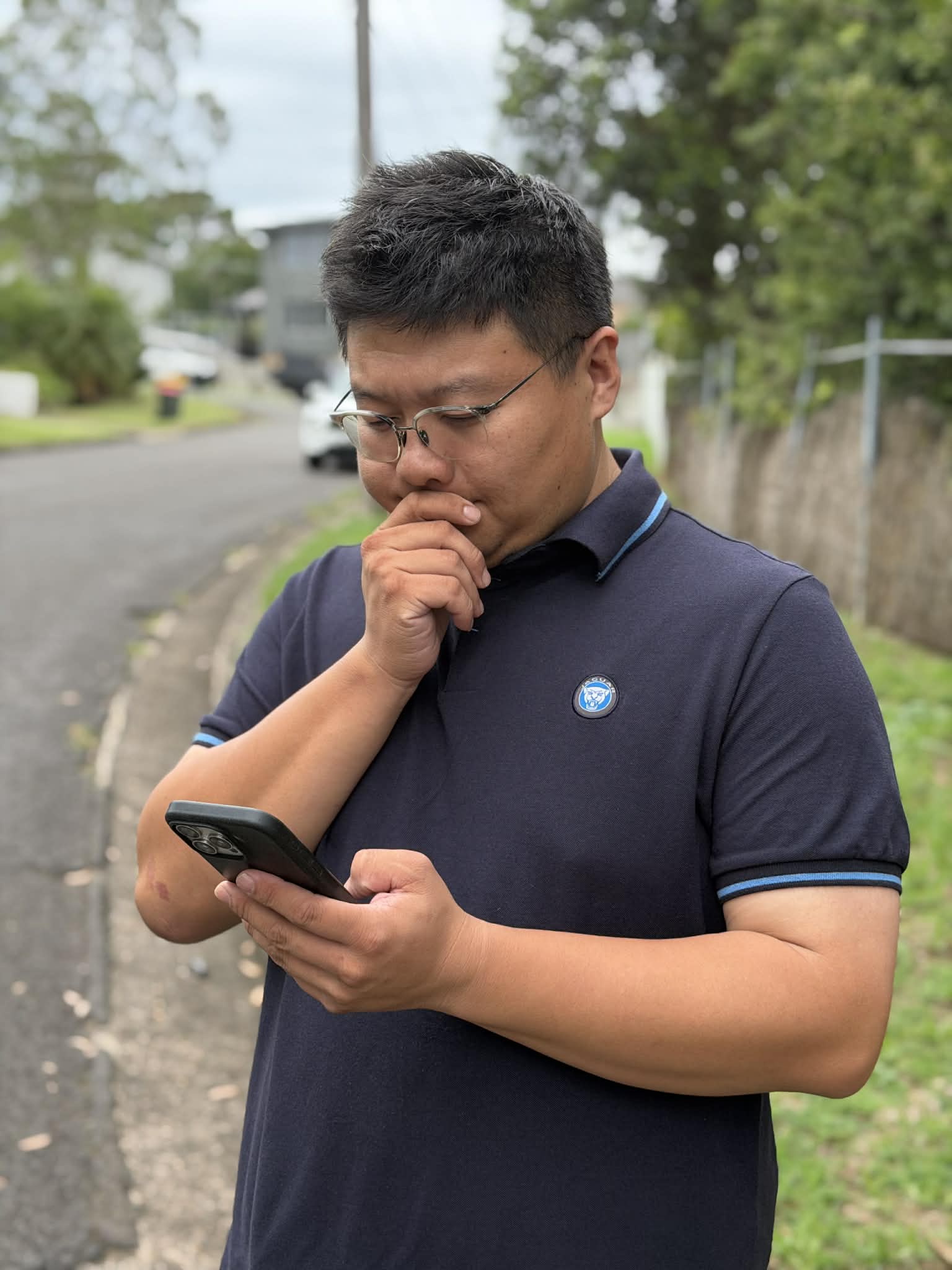 A photo of Billy standing outside and looking at his phone.