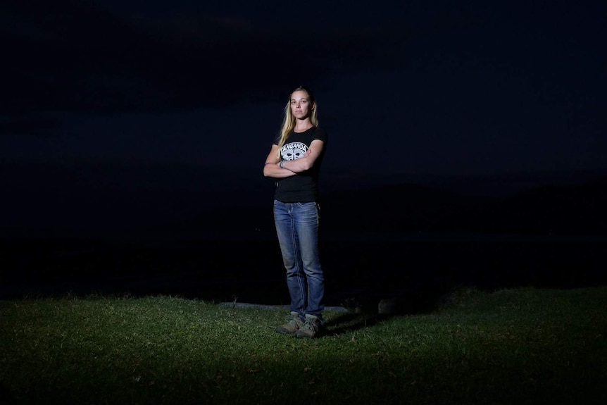 A photo of Vanessa Carey standing with folded arms on a beach, at night, near Cairns.