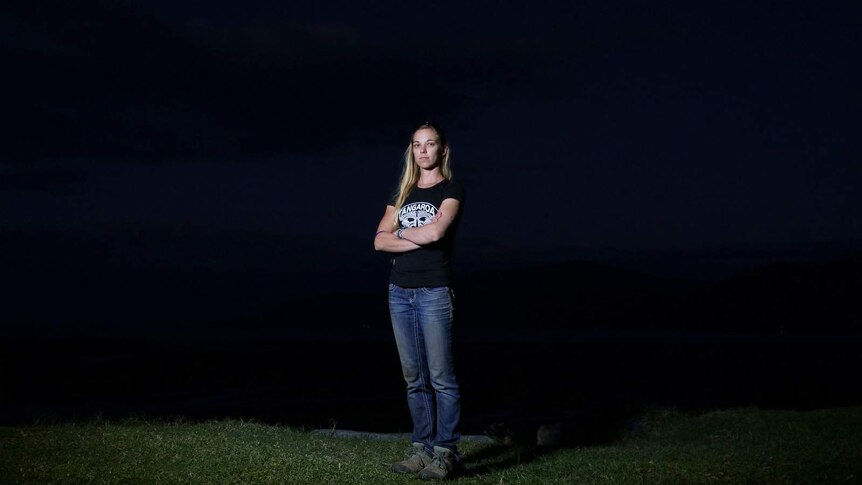 A photo of Vanessa Carey standing with folded arms on a beach, at night, near Cairns.