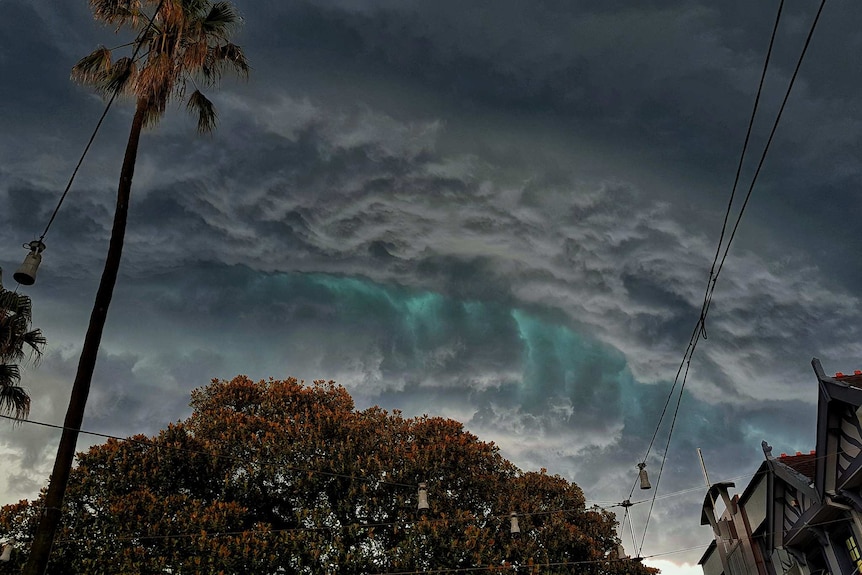 green storm clouds loom over trees and houses
