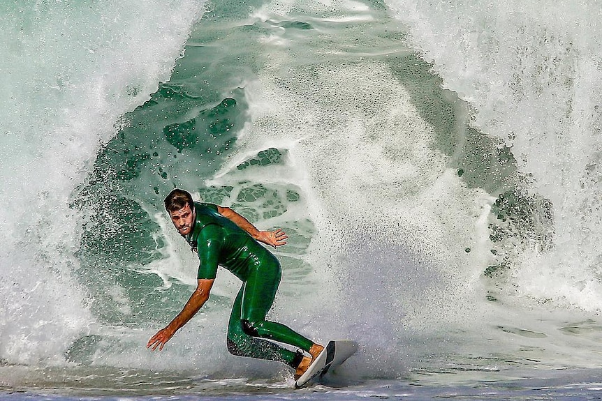 A surfer in a green wetsuit catches a green wave