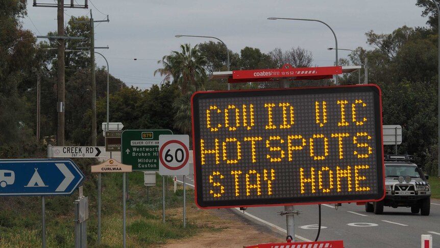 A digital road sign reads Covid Vic hotspots stay home.
