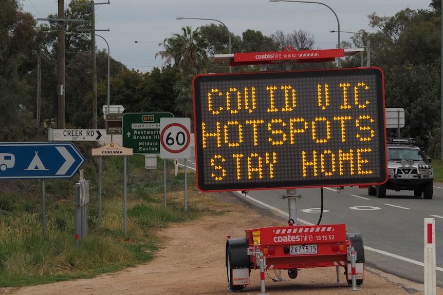 A digital road sign reads Covid Vic hotspots stay home.