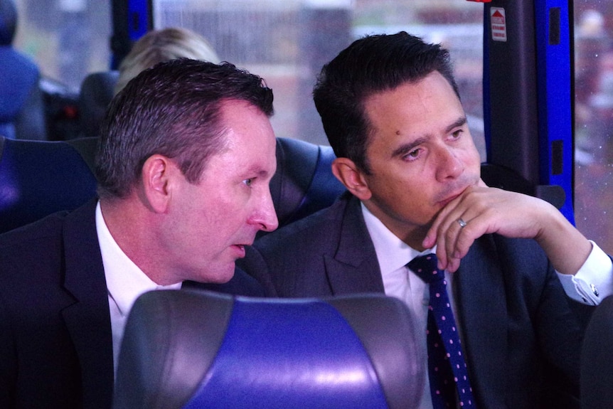 WA Treasurer Ben Wyatt and Premier Mark McGowan talk while sitting on a bus.