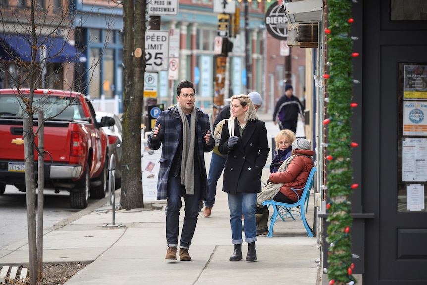 Actors Daniel Levy and Kristen Stewart walking down a city street in the movie Happiest Season
