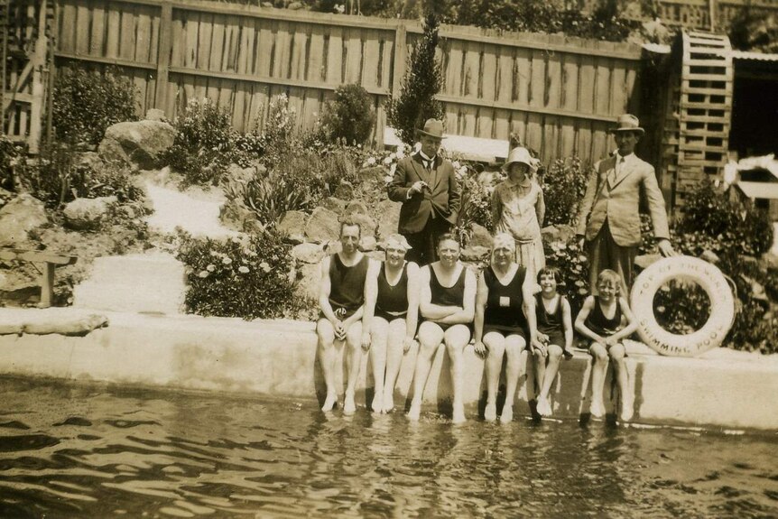 Black and white photo of swimmers sitting at a pool