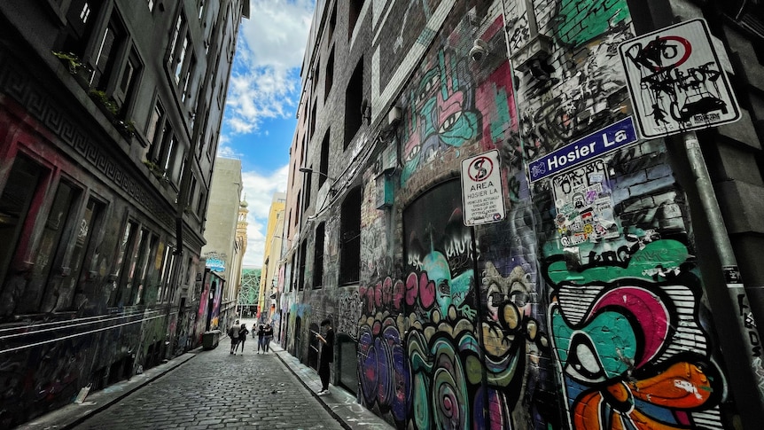 Graffiti across walls of Hosier Lane in Melbourne, people seen to the distance.
