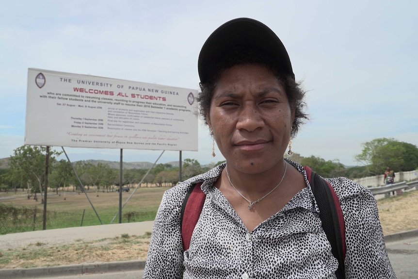 Tracy Ponak stands in front of the University of Papua New Guinea welcome all students sign