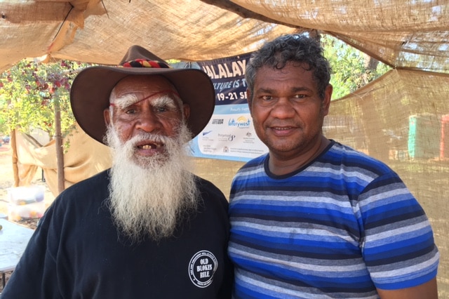 An Indigenous father and son standing side by side.