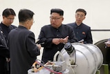 Kim Jong-un talks to experts around a missile.