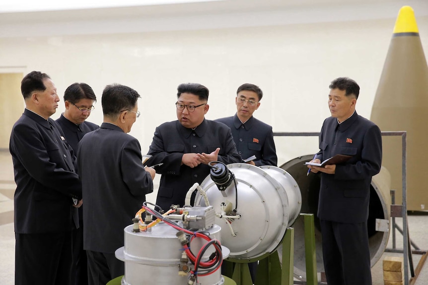 Kim Jong-un talks to experts around a missile.