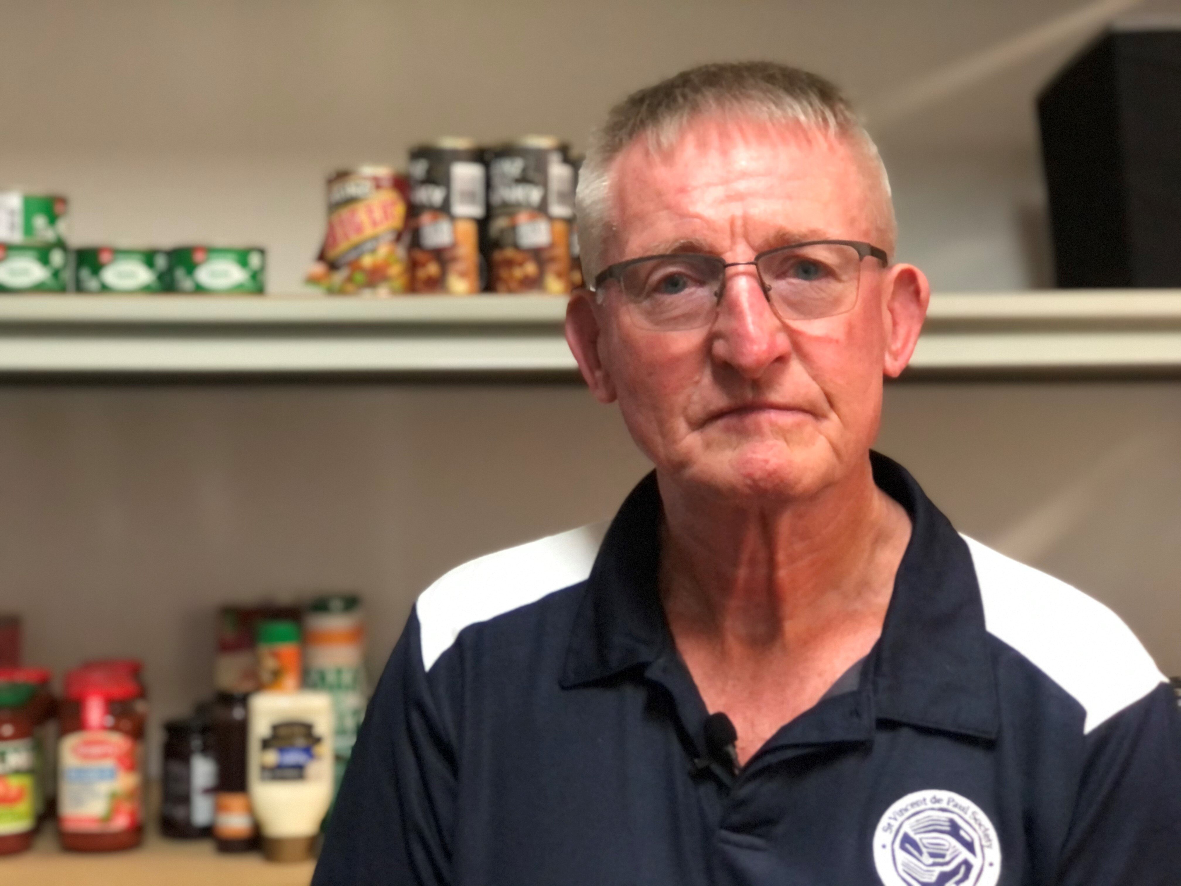 Man stand in front of shelves of canned food