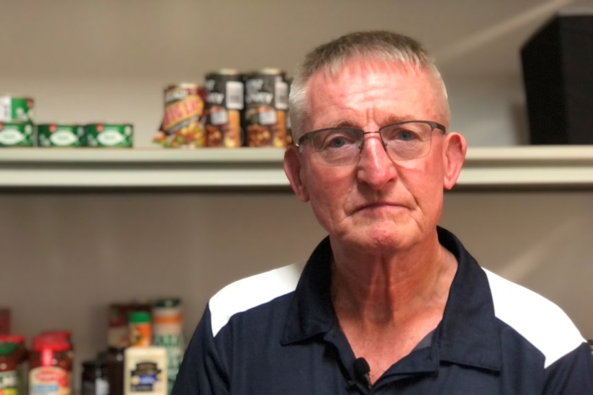 Man stand in front of shelves of canned food