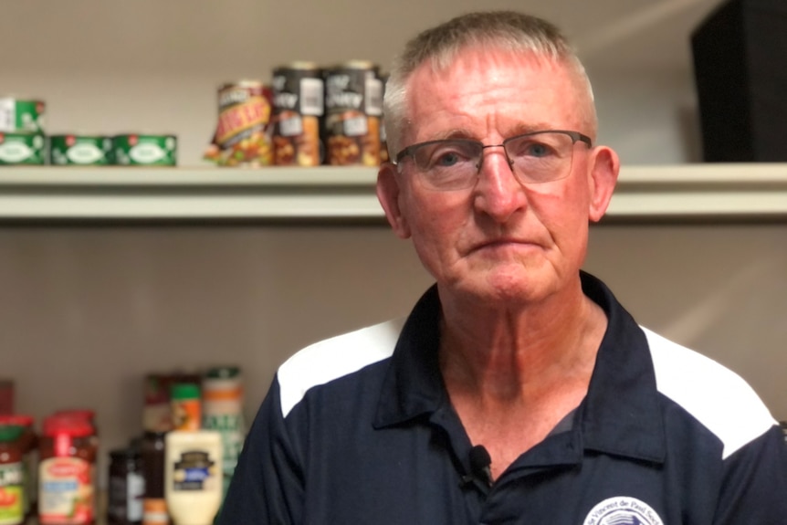 Man stand in front of shelves of canned food