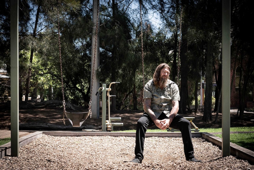 Ben Felton sitting on a child's swing.