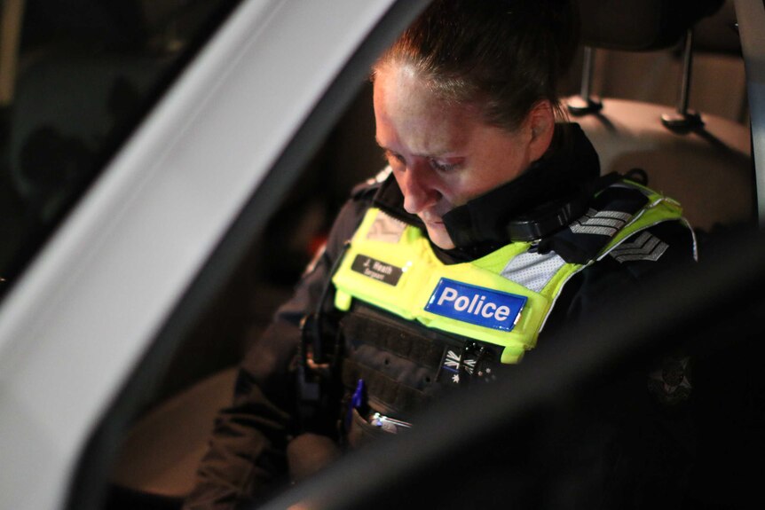 A female police officer sitting in the front seat of a police vehicle.