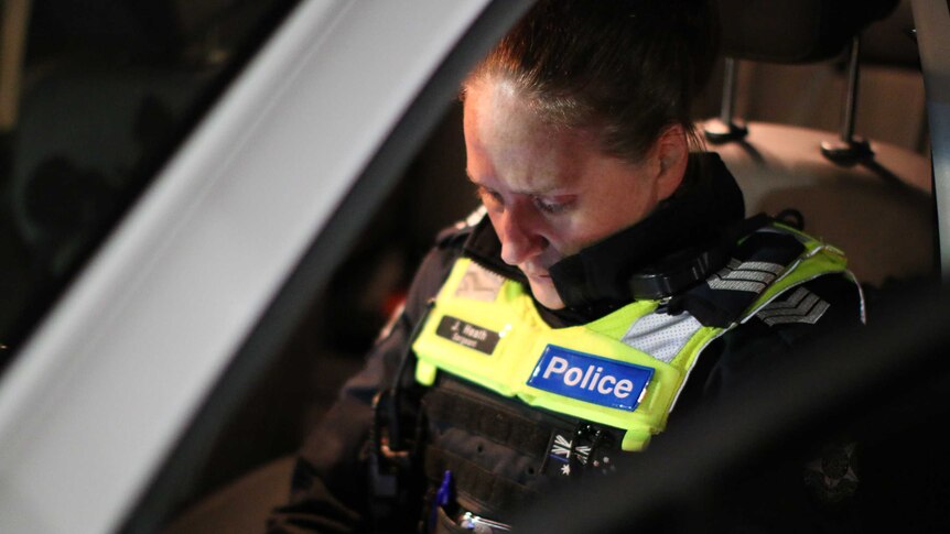 A female police officer sitting in the front seat of a police vehicle.
