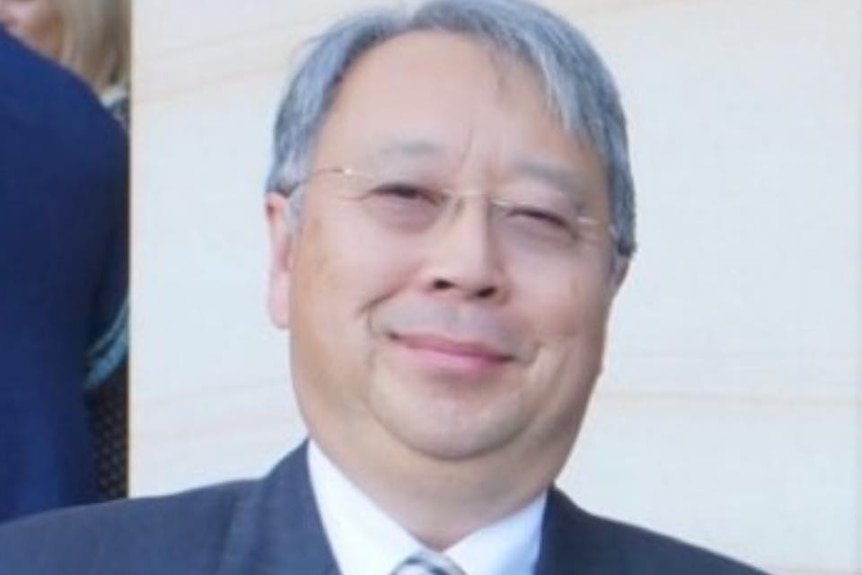 A picture of a man with grey hair and glasses smiling. 