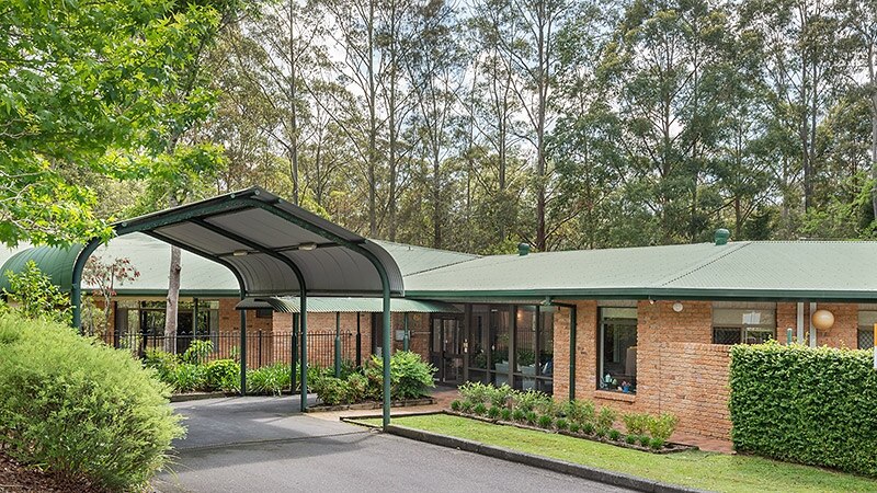 The Henry Kendall aged care facility is a brick building with a green roof, hedge, lawn and driveway