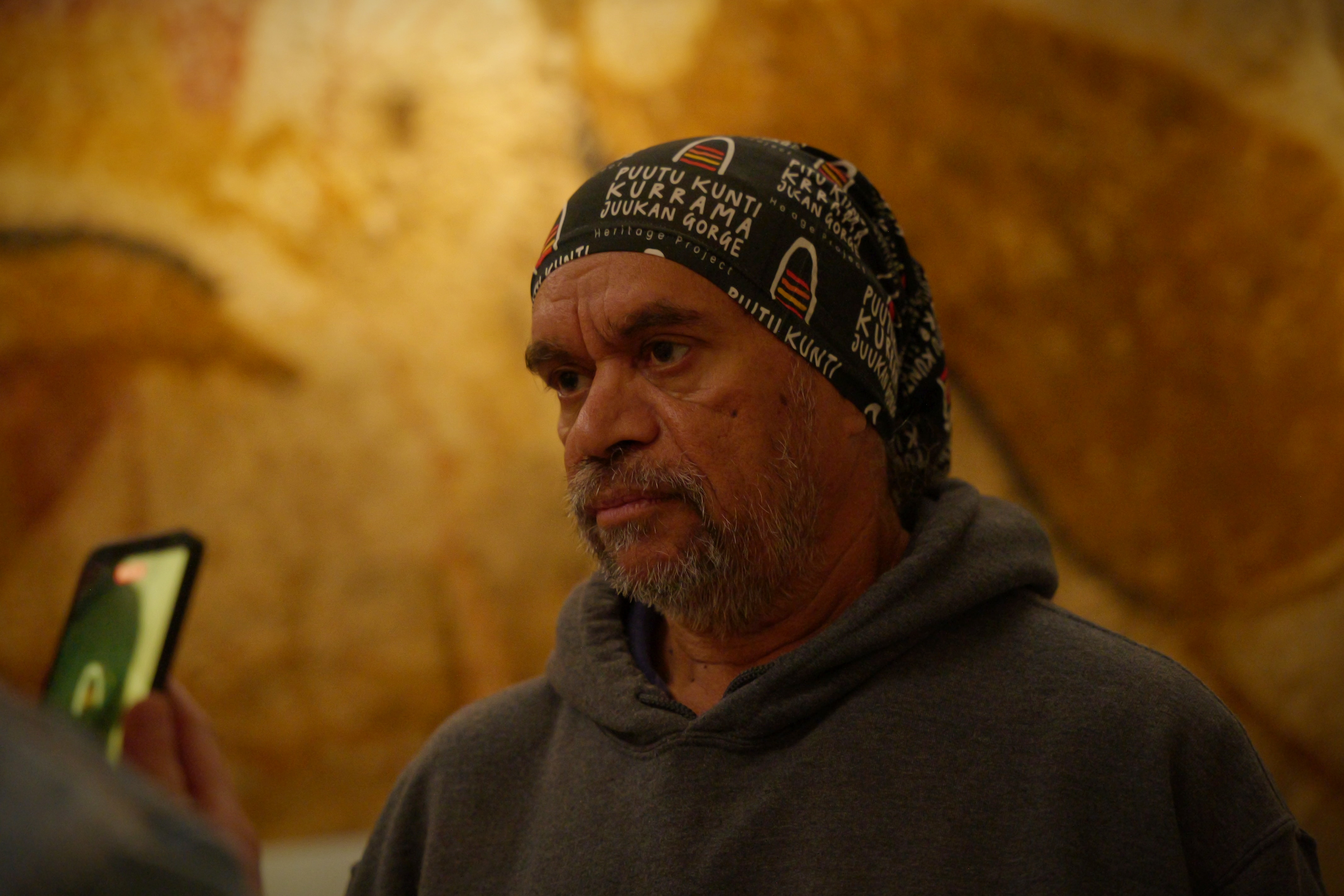 Um homem com um lenço conversa com um jornalista numa caverna.