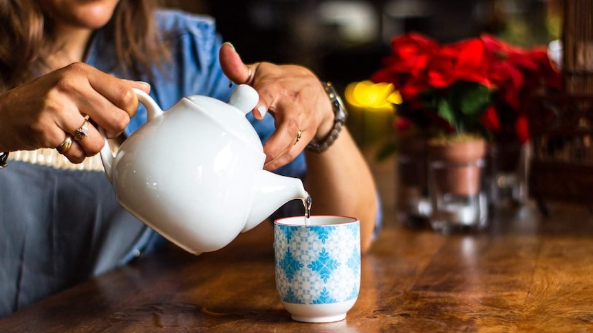 A woman pours from a teapot.
