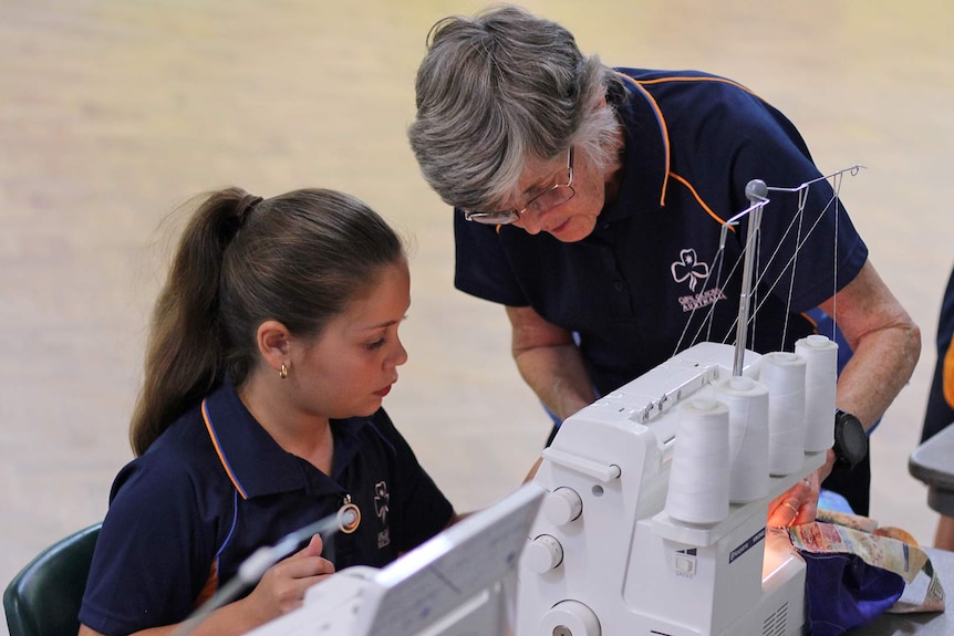 Girl Guide leader Deirdre Ryan instructs one of the girl guides on how to use a sewing machine.