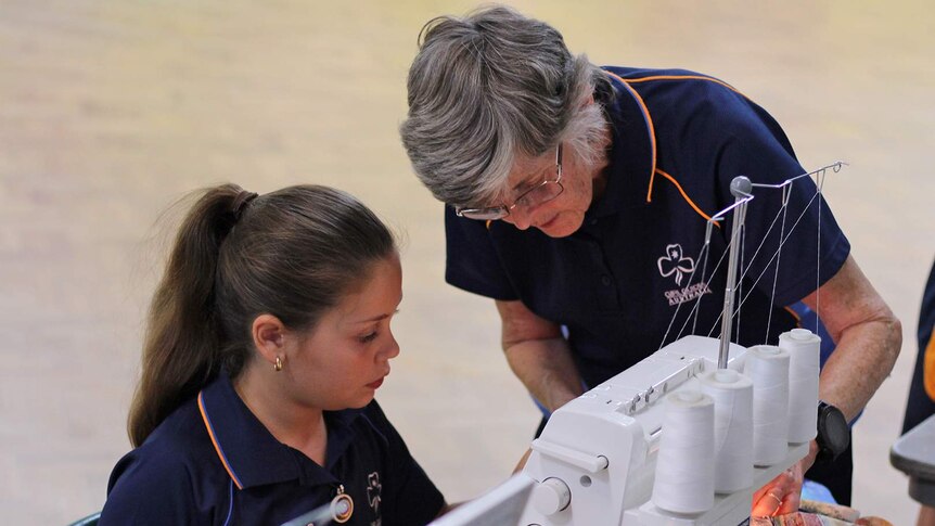 Girl Guide leader Deirdre Ryan instructs one of the girl guides on how to use a sewing machine.