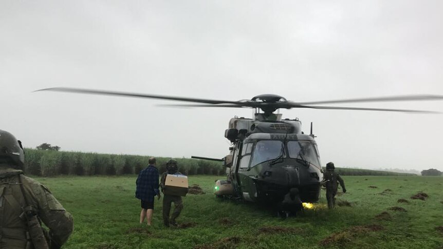 Soldiers arrive in a helicopter at a school camp near Tully to deliver supplies.