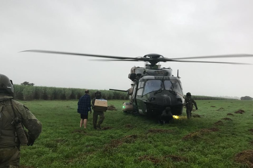 Soldiers arrive in a helicopter at a school camp near Tully to deliver supplies.