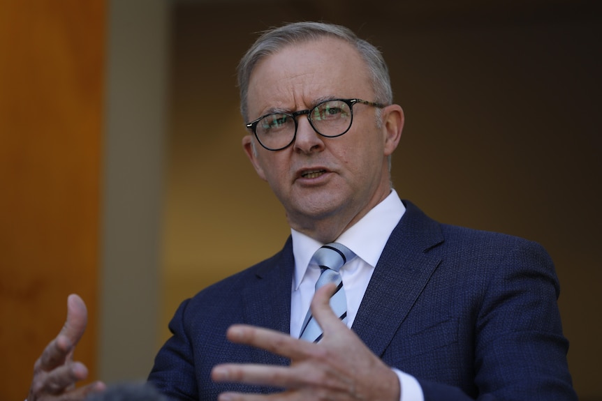 Anthony Albanese mid-sentence while gesturing with his hands, the background is out of focus