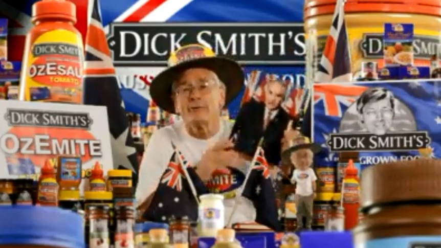 A man surrounded by flags and large products