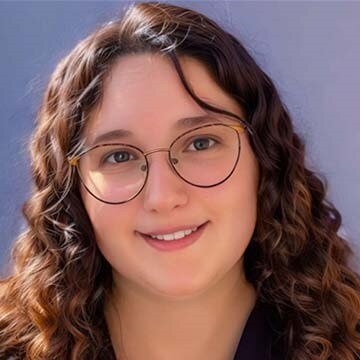 A young woman with glasses and long brown wavy hair.