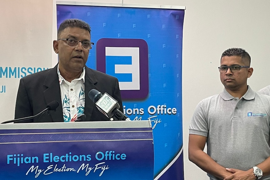 A man in suit and a man in grey shirt at a press conference in Suva. 