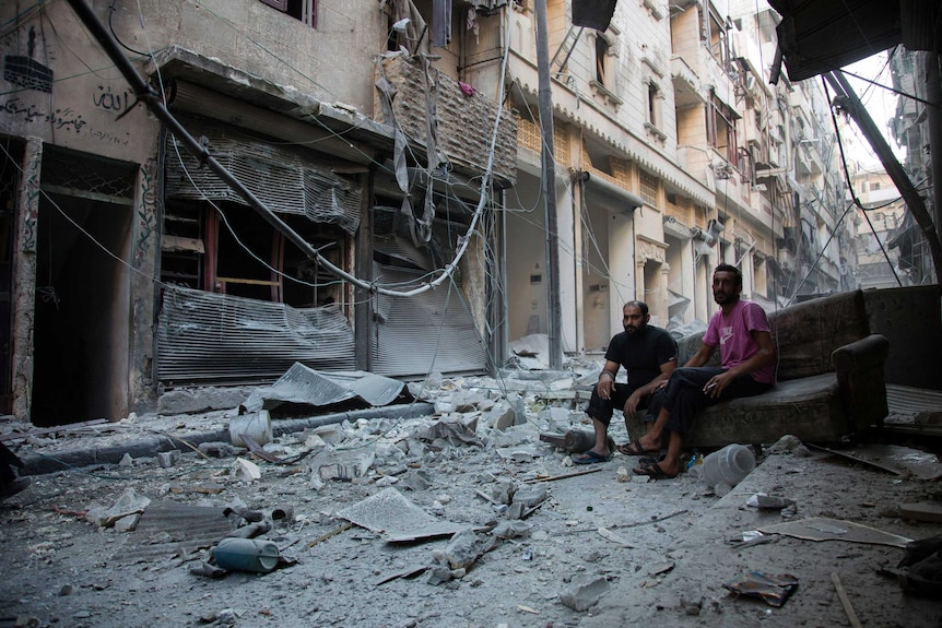 Syrians walk through the rubble in Karm al-Jabal.